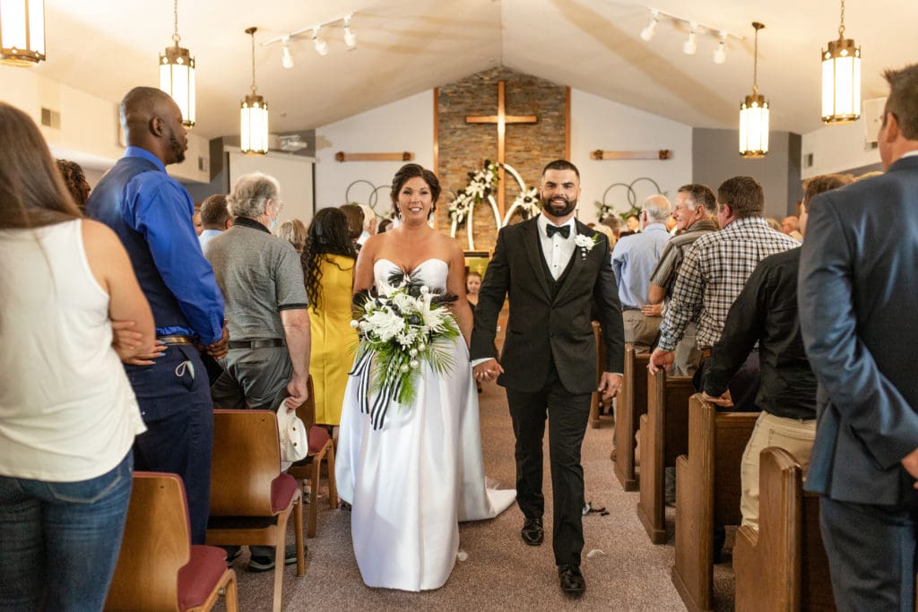 husband and wife walking down the aisle, Lutheran church wedding, family and friends embrace bride and groom