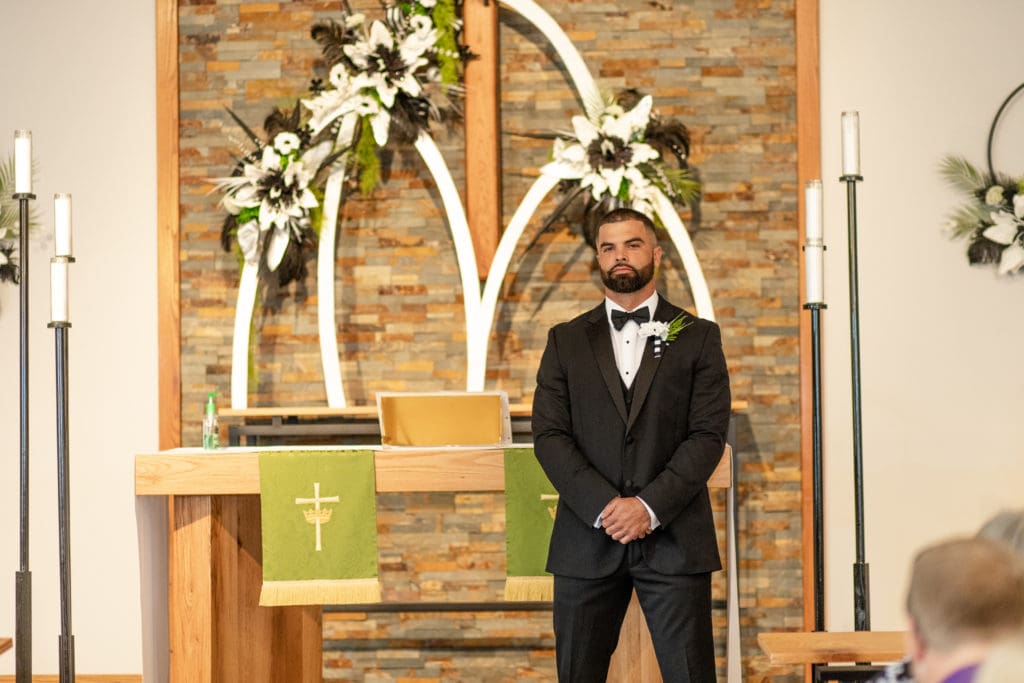 groom awaits for bride, groom at altar, black tuxedo and black bowtie, church wedding decoration, southern illinois Lutheran church wedding